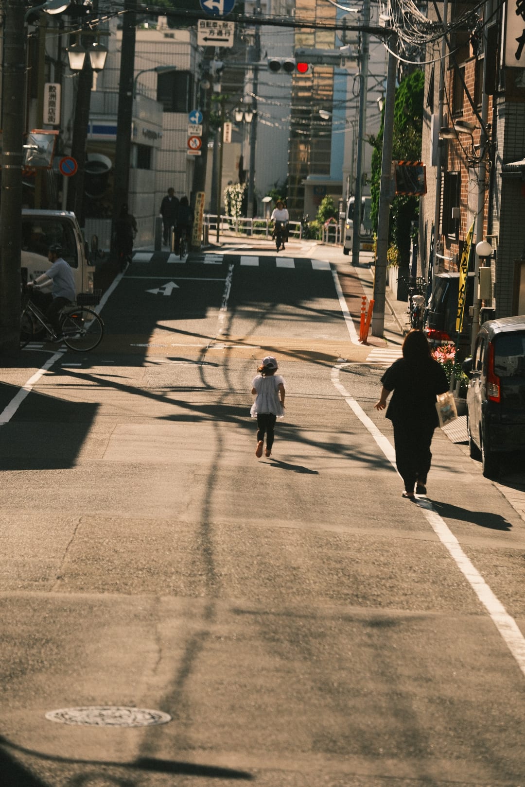 Two figures walking a shopping street in raking afternoon light