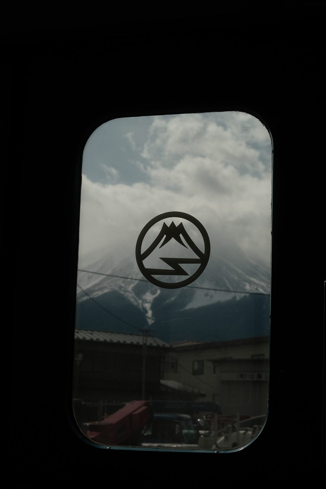 Mount Fuji seen through a train window with a circular mountain decal on the glass