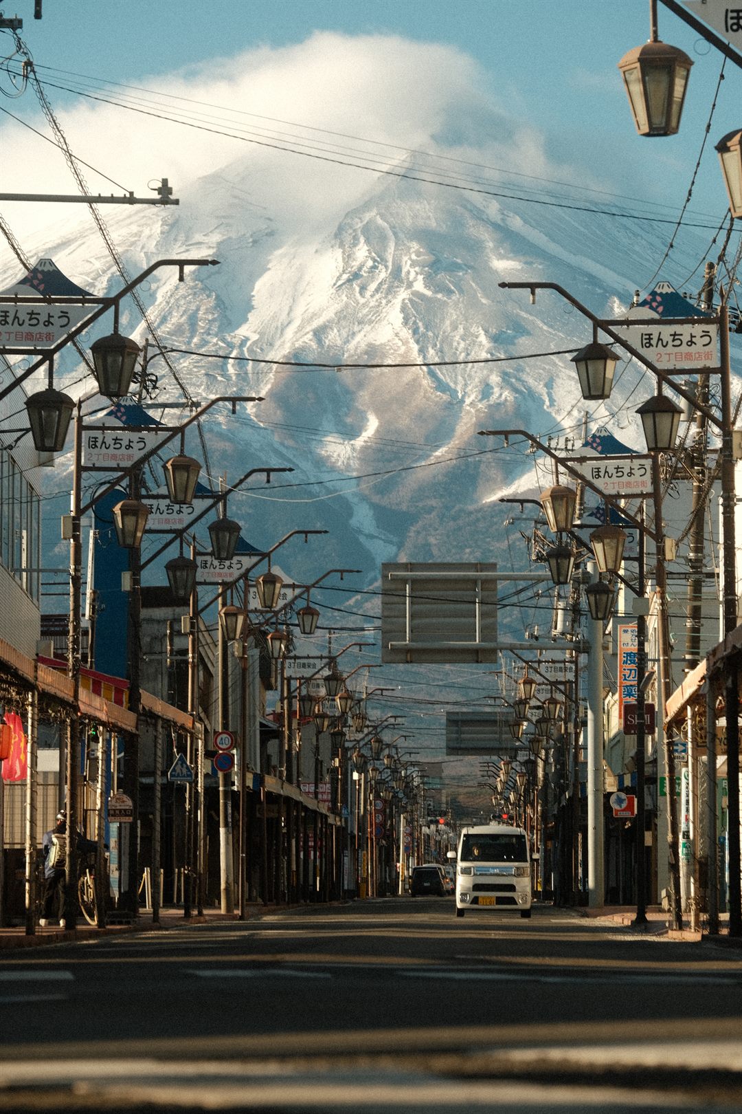 An empty shopping street lined with lanterns, Mount Fuji closing the view at the end
