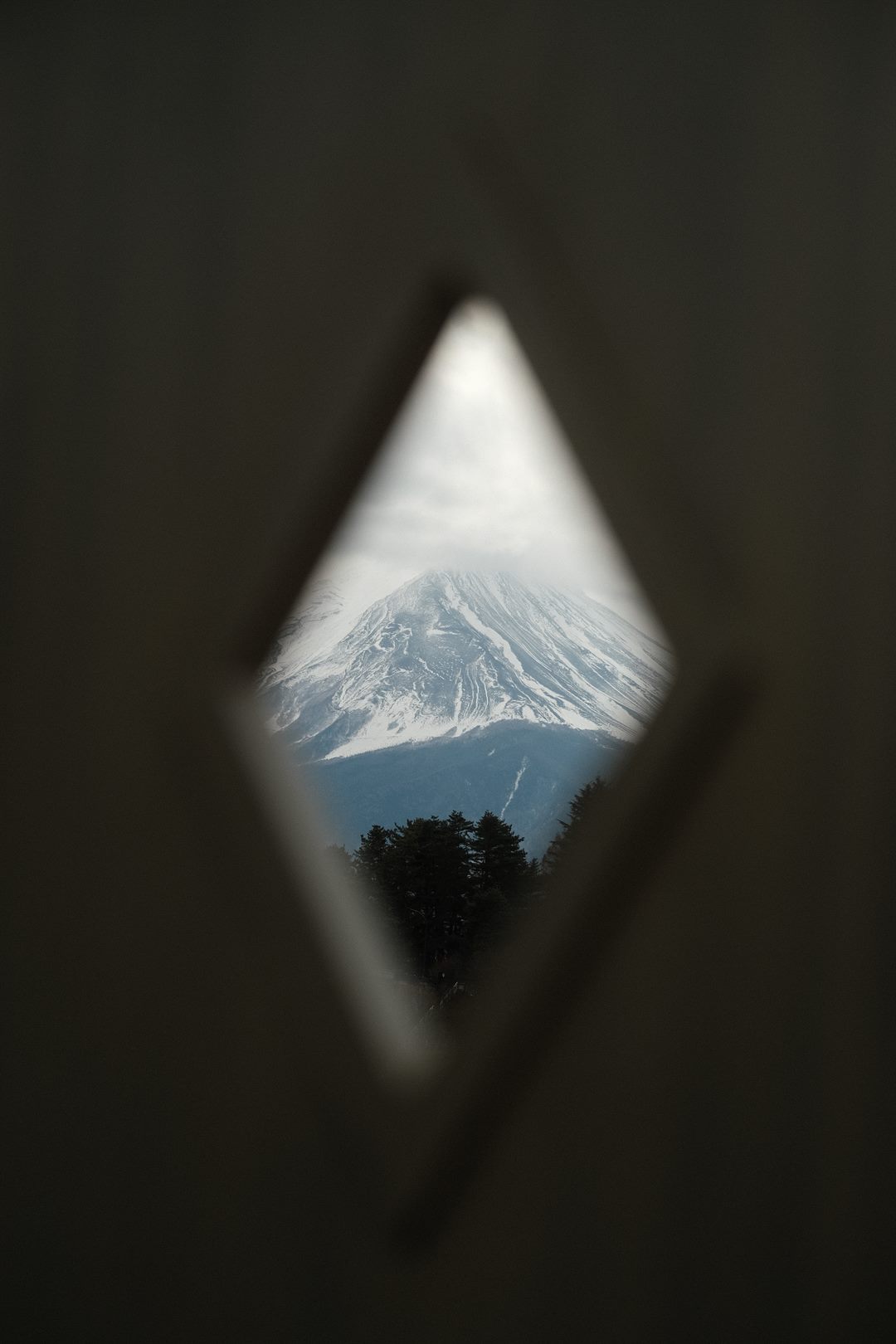 Mount Fuji framed by a diamond-shaped opening cut in a dark wall
