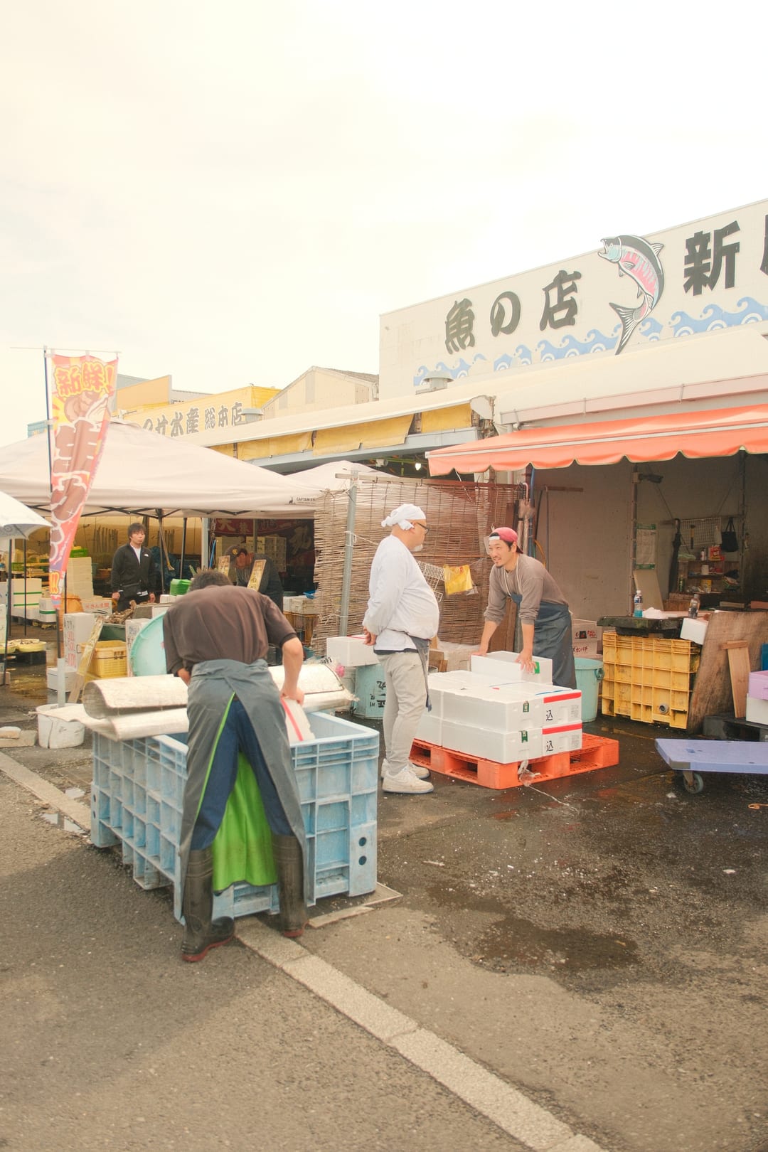 A worker in an apron moving crates outside a fishmonger's stall at dawn