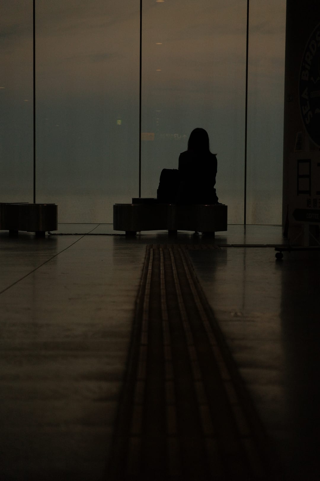 A lone figure silhouetted against the station's full-height sea windows