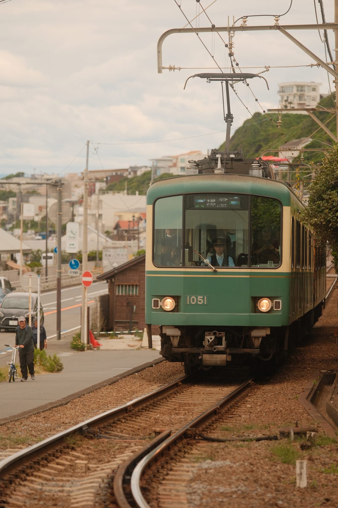 A green and cream tram coming head-on down the single track